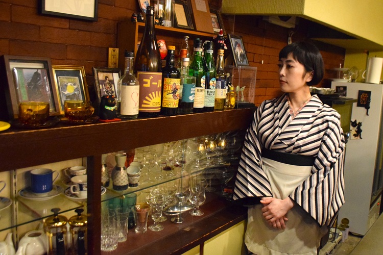 Utsugi parle de ses sentiments envers ses clients devant une étagère présentant sa vaisselle et ses accessoires préférés.