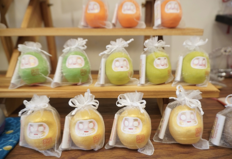 Poupée Daruma de la série « Mamehapi », accompagnée d'un petit papier de prédiction.