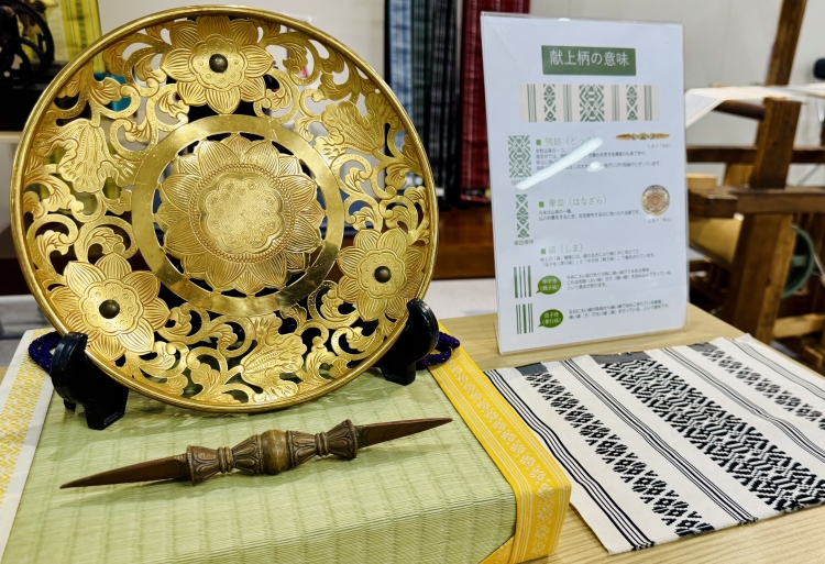 Les instruments bouddhistes représentés dans le dessin forment un motif d'hommage : en bas à gauche : dokko (un type de vajra), en haut à gauche : hanazara (un type d'assiette à fleurs).