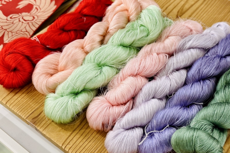 Fil de soie blanche fabriqué à partir de cocons de vers à soie, teint avec des colorants.