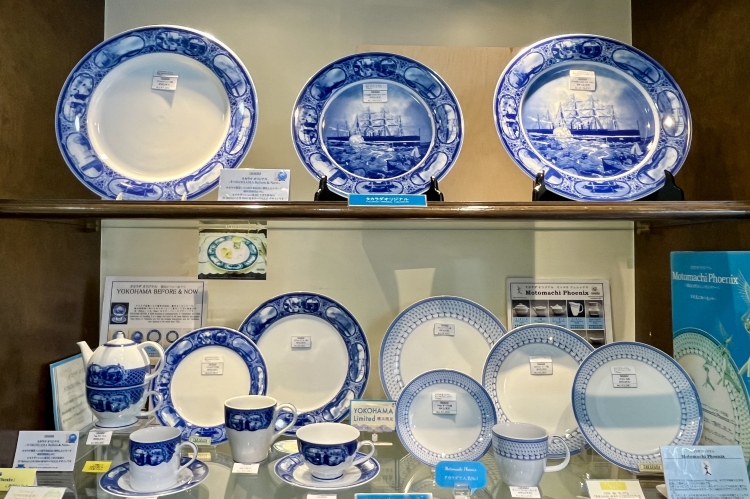 Une série originale d'assiettes décoratives, de tasses et autres articles représentant des paysages de Yokohama dans un bleu éclatant.