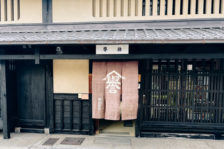 Un noren digne (rideau traditionnel japonais) avec le caractère « 誉 » (honneur) affiché en évidence.