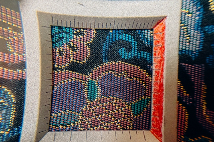 Observé à la loupe, on constate clairement que le tissu est tissé à partir de trois fils de couleurs différentes.