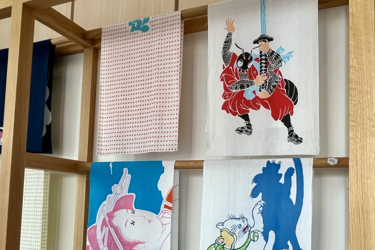 Un tenugui (serviette japonaise) orné d'un rébus. Dans le coin supérieur droit figure une fourmi tenant une épée, ce qui signifie « merci ».