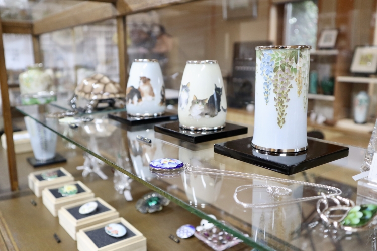 Une variété d'objets en émail cloisonné est exposée dans la vitrine du magasin.