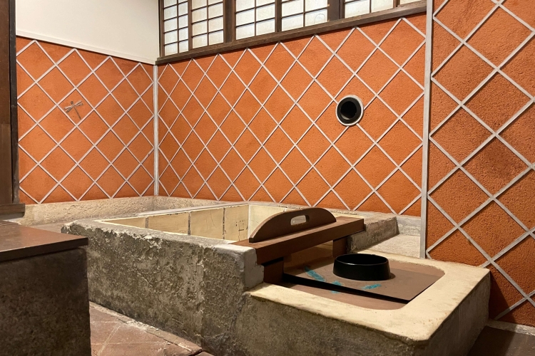 Une baignoire avec un chaudron en fer et des plaques de séparation permettant de contrôler la température de l'eau.