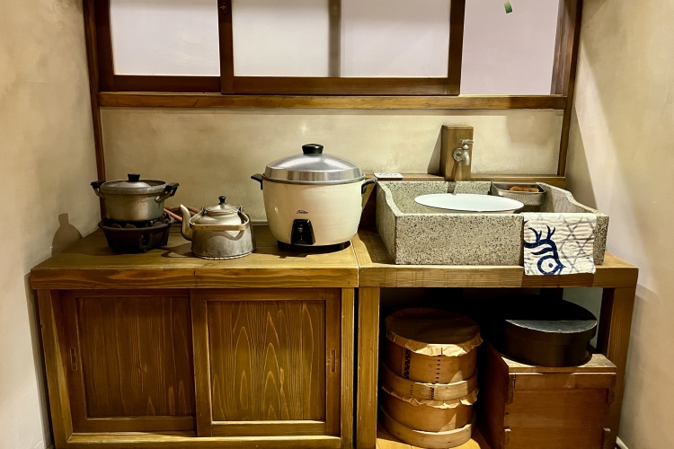 Une cuisine reconstituée des années 1950. On y trouve un mélange d'objets ménagers anciens et modernes.